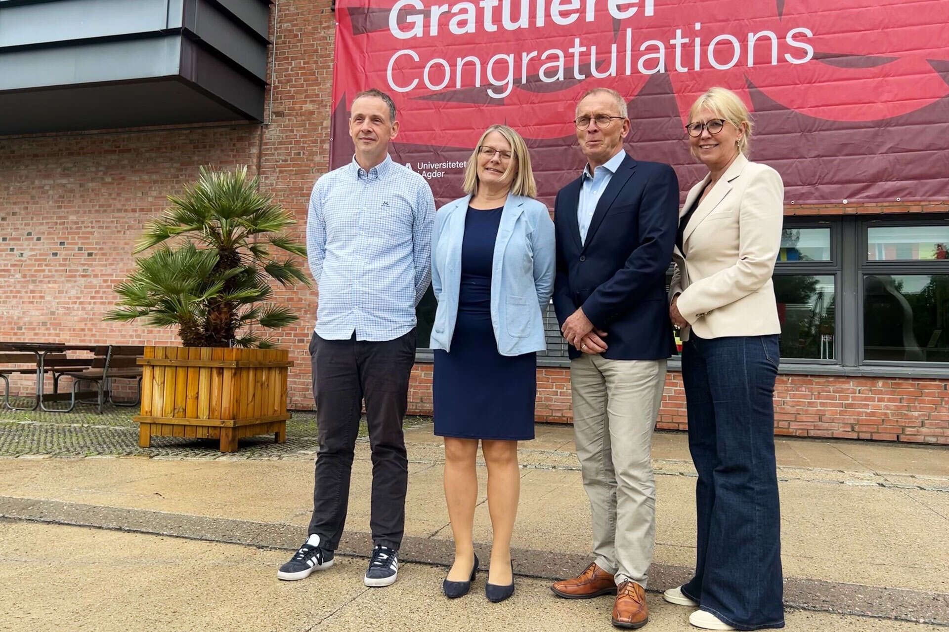 Stephen Sayfritz (RD&I Manager, GCE NODE), Sunniva Whittaker (Rector, UiA), Knut Mjåland (CEO, GCE NODE), and Gøril Hannås (Vice-Rector, UiA) in front of a sign saying "Congratulations"