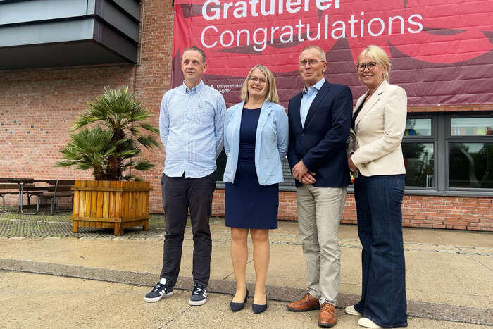 Stephen Sayfritz (RD&I Manager, GCE NODE), Sunniva Whittaker (Rector, UiA), Knut Mjåland (CEO, GCE NODE), and Gøril Hannås (Vice-Rector, UiA) in front of a sign saying "Congratulations"