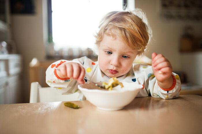 Mann med forkle som smaker på mat