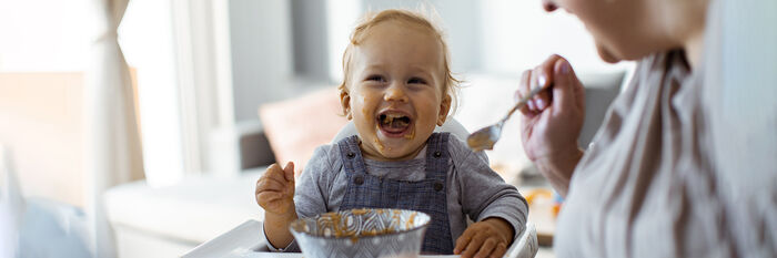Mann med forkle som smaker på mat