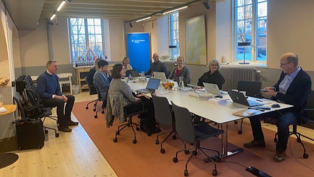 8 personer rundt et møtebord, pc 
