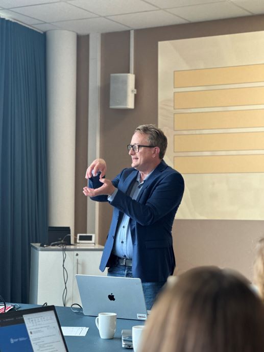 mann i blå blazer som presenterer foran et bord
