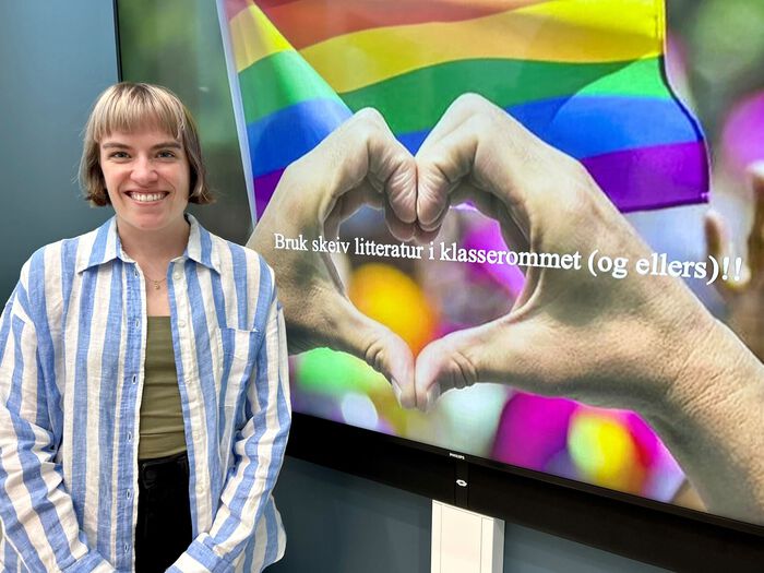 En smilende person foran regnbueflagg