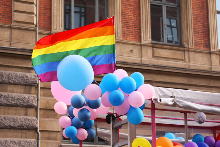 Prideflagg veivende sammen med rosa og blå ballonger
