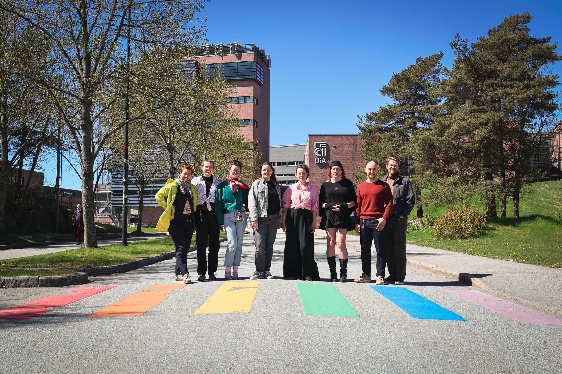 Group photo in front of the Kristiansand campus, with everyone standing in front of the rainbow pedestrian crossing