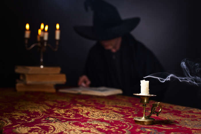 Illustration of a witch wearing a black hat and reading