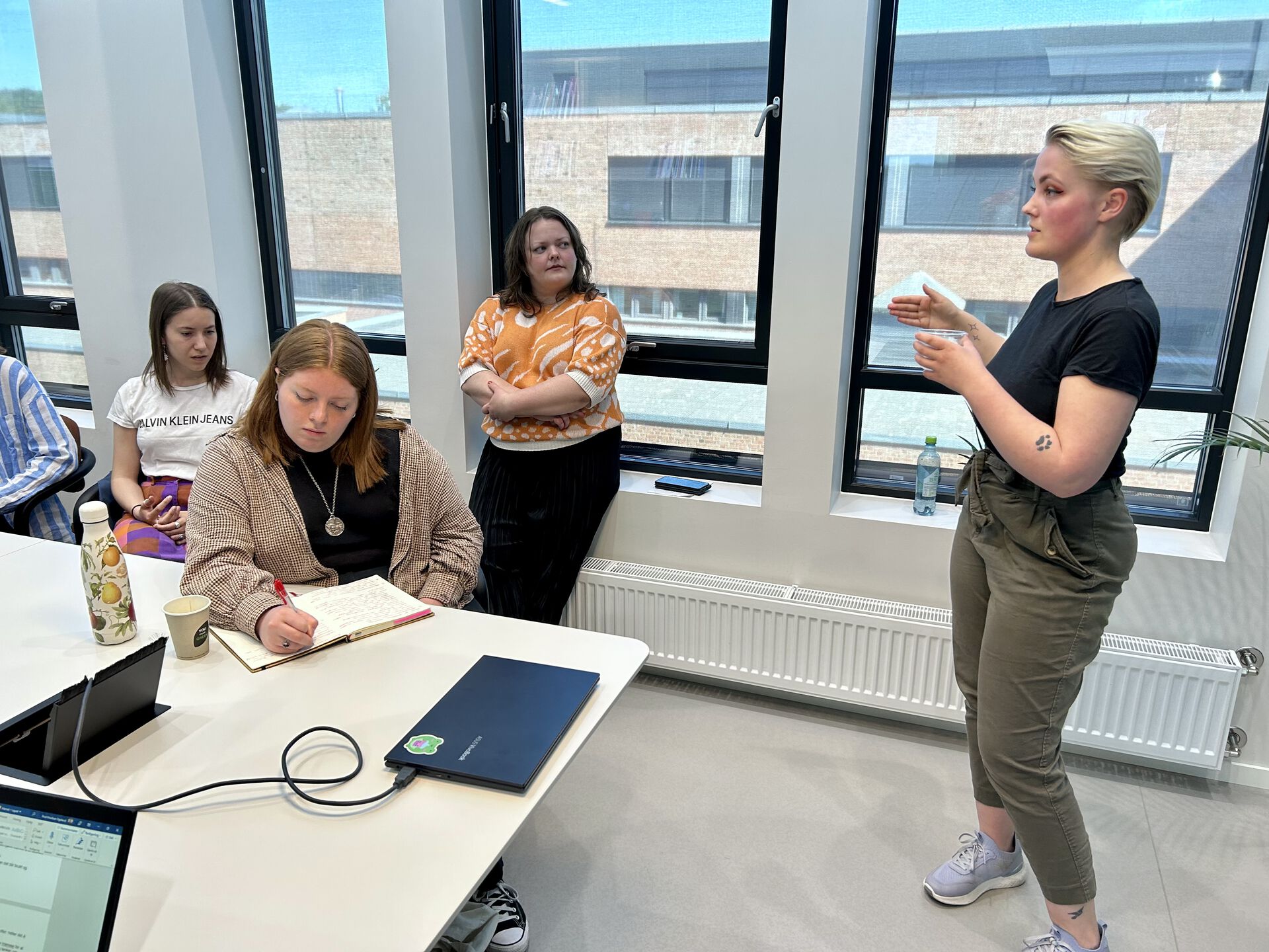 Nora Christiansen står ved et bord og forklarer overfor tilhørere.