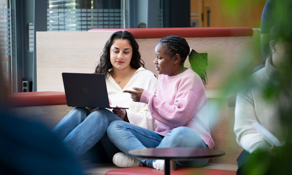 To kvinnelige studenter diskuterer noe over en PC