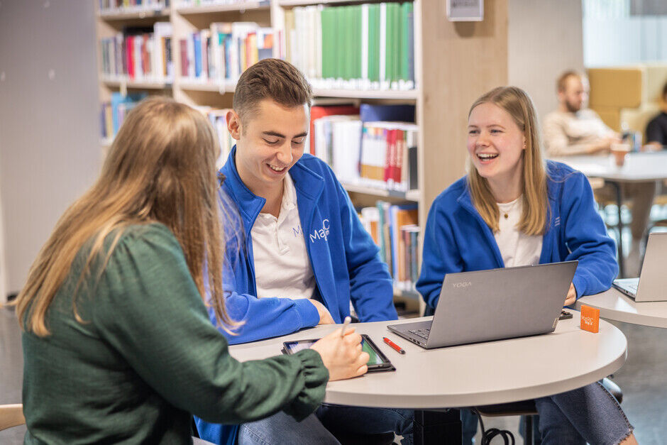 Fem studenter foran hovedinnganga til UiA i Kristiansand, ved et regnbue-gangfelt
