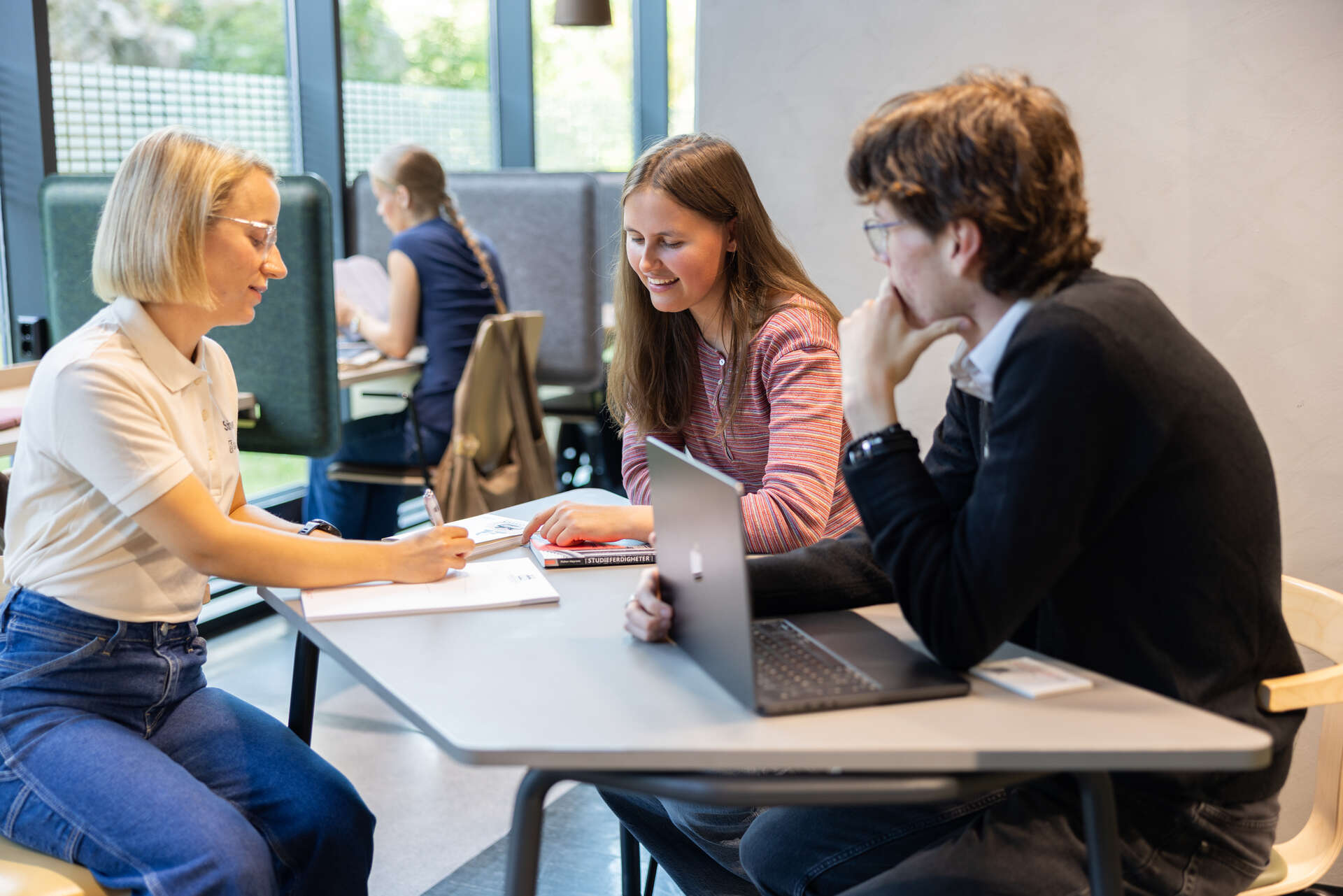 Tre studenter snakker sammen