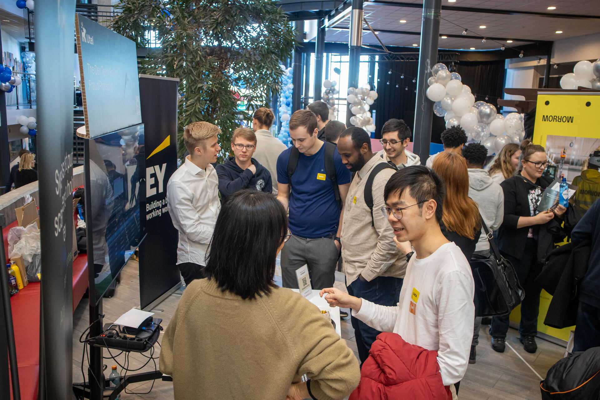 Engasjerte studenter snakker med noen på stand fra EY. 