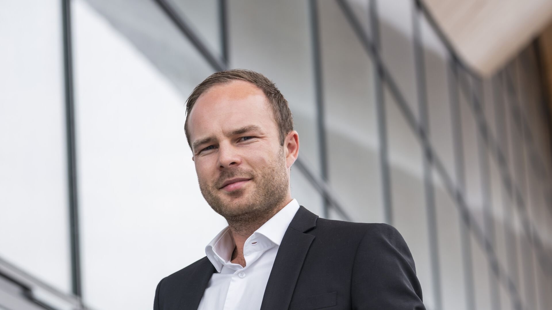 Portrettfoto av Erlend Falck foran glassbygg