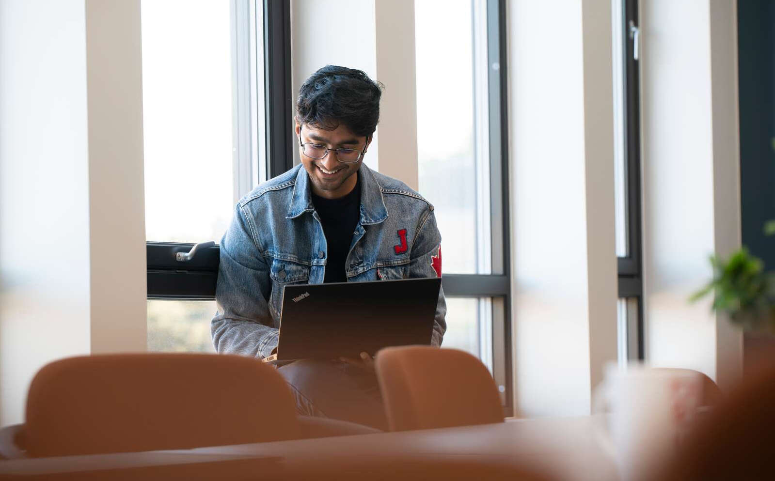 En smilende mann som sitter og leser noe på pc-en sin