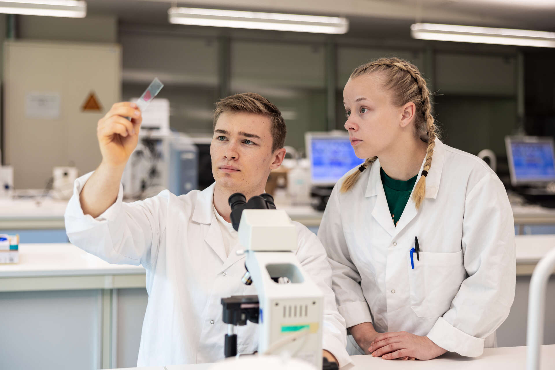 En gutt og en jente med hvite frakker i et laboratorium