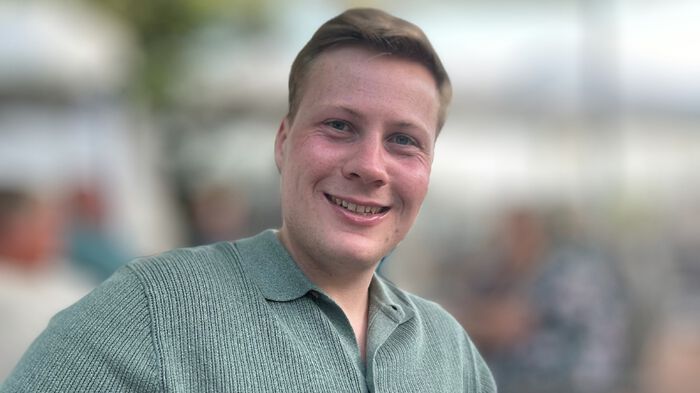 Portrett av en mann med kort hår og blå t-skjorte. 