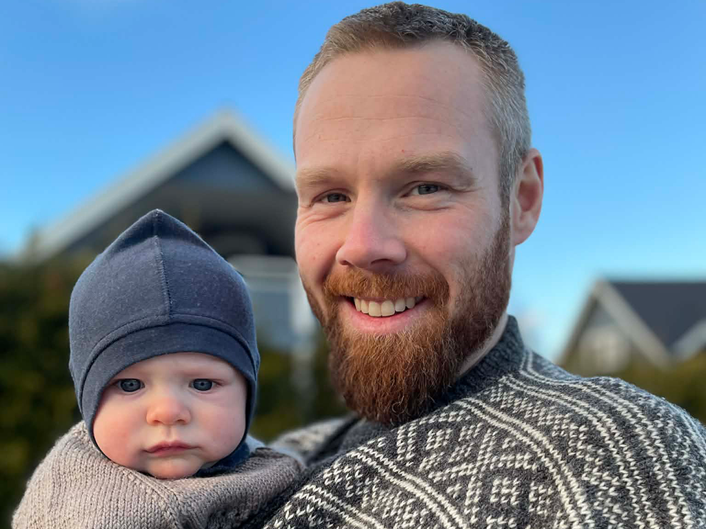 Dag Thomas holder sønnen sin og smiler til kamera