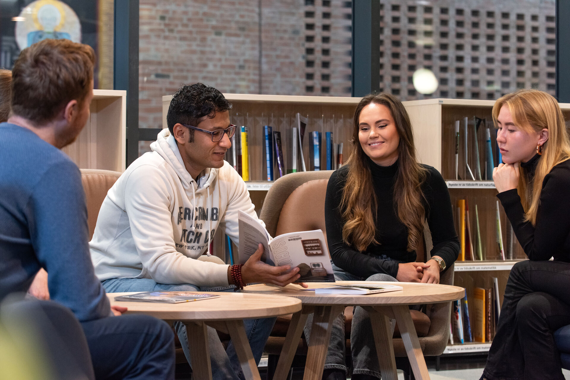 Fire studenter sitter i biblioteket og diskuterer