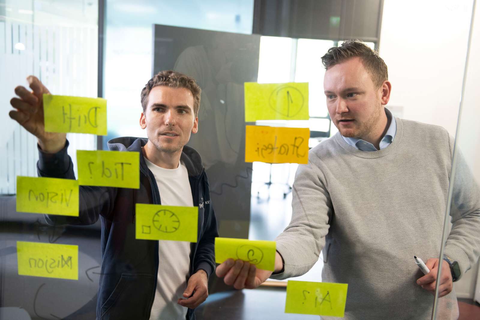 To unge menn henger ide-lapper på vegg