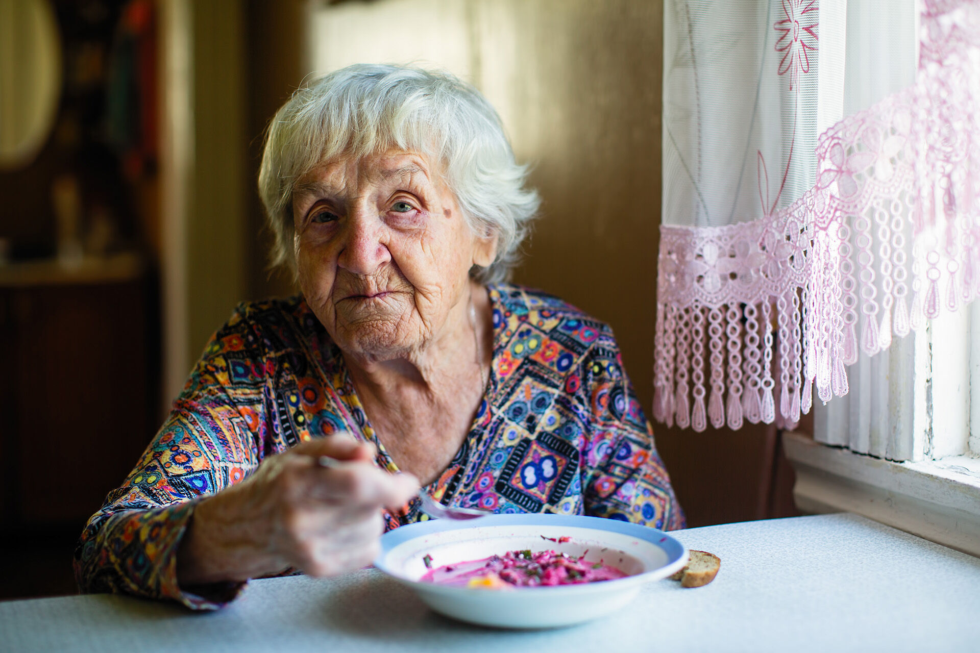 En eldre mann og en eldre kvinne ser på hverandre og smiler bak et bord med grønnsaker 