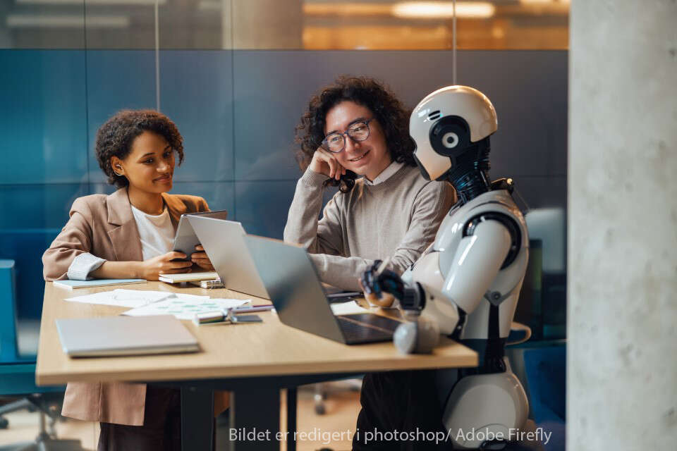 To kvinner og en robot sitter sammen og jobber med PC