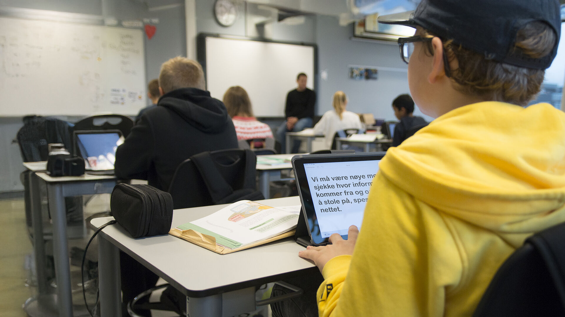 Tre voksne studenter som sitter rundt en PC og diskuterer 