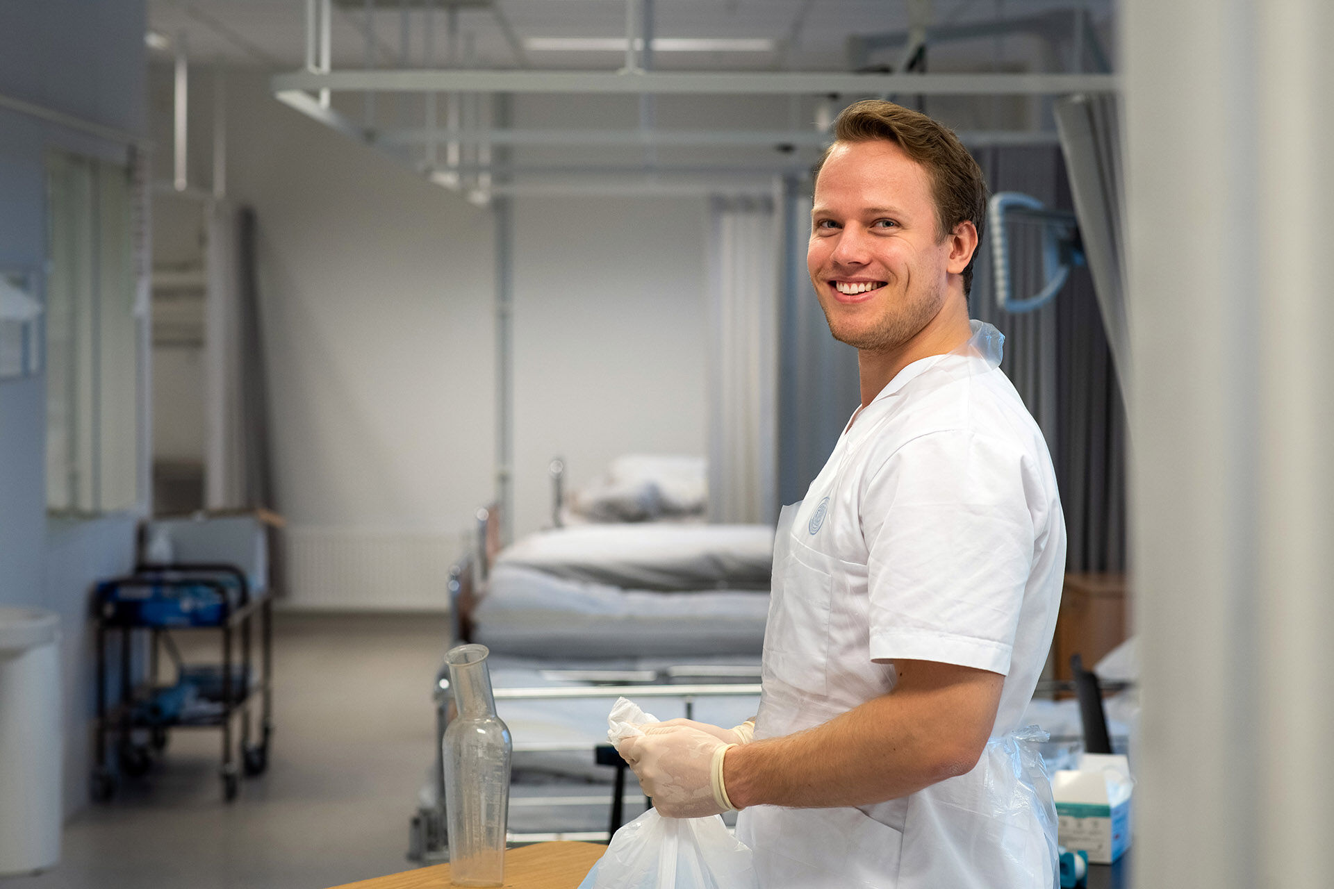 To kvinner og en mann i hvite frakker som øver på sykepleieprosedyrer 