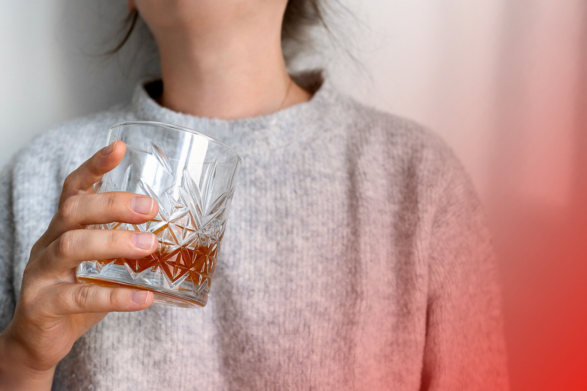 En hvit kvinne holder et glass med alkoholholdig drikke