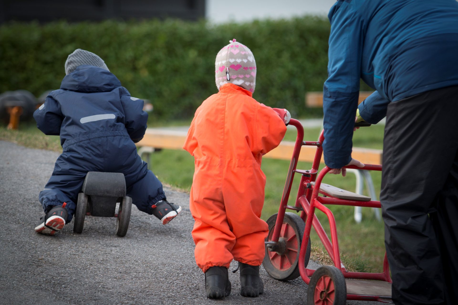 To små barn ute og sykler i barnehagen