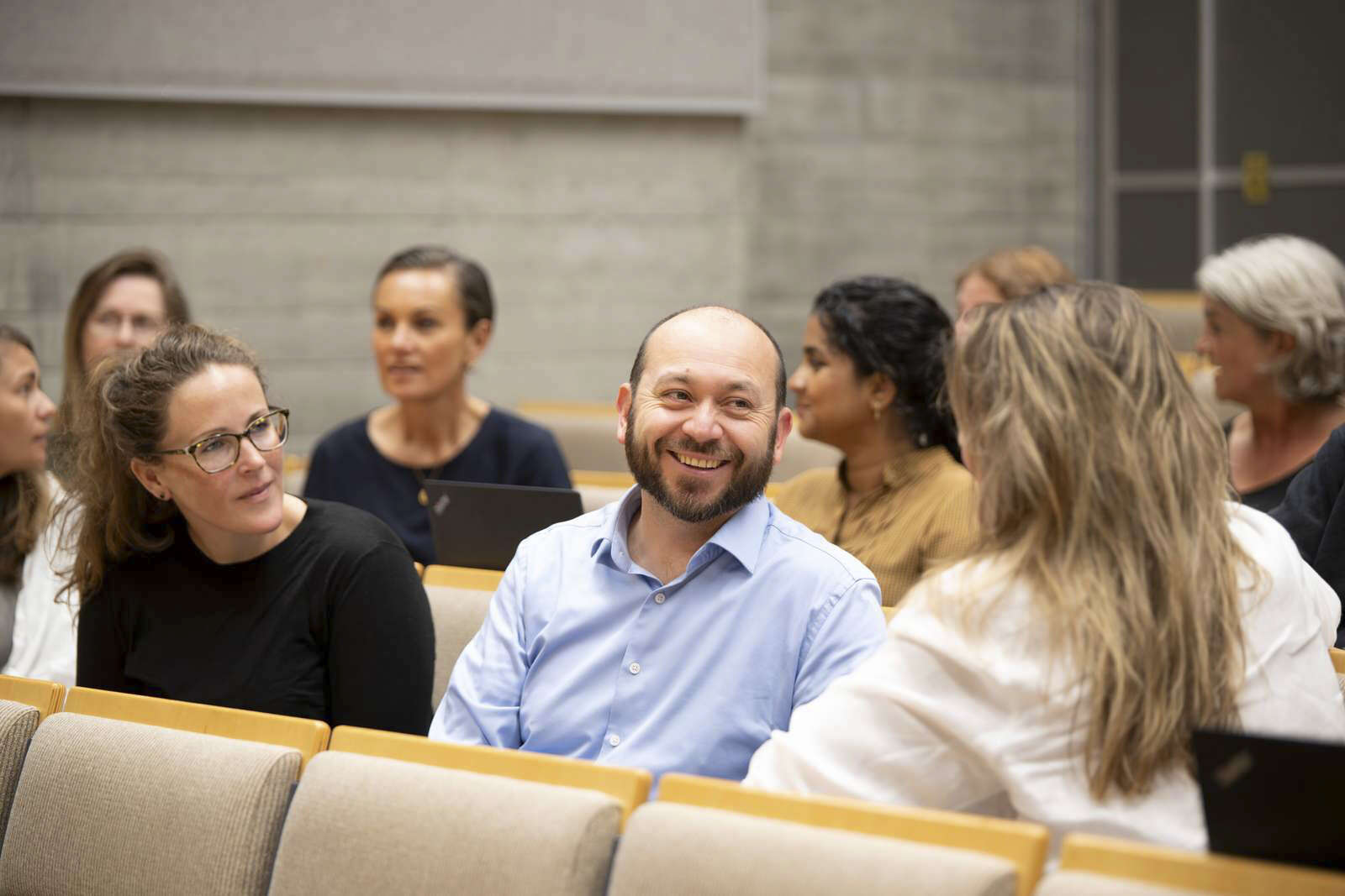 Menn og kvinner på en arbeidsplass tar et fellesbilde hvor de smiler og holder rundt hverandre
