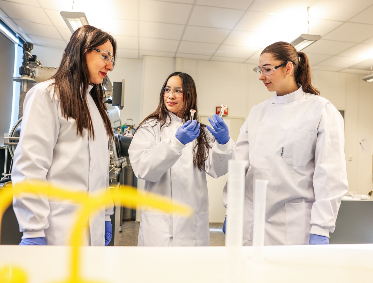 Tre studenter som snakker sammen på et laboratorium