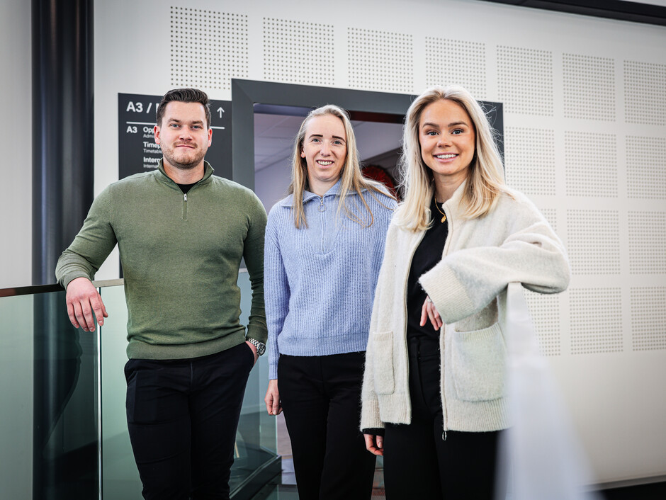 Tre studenter poserer sammen og smiler