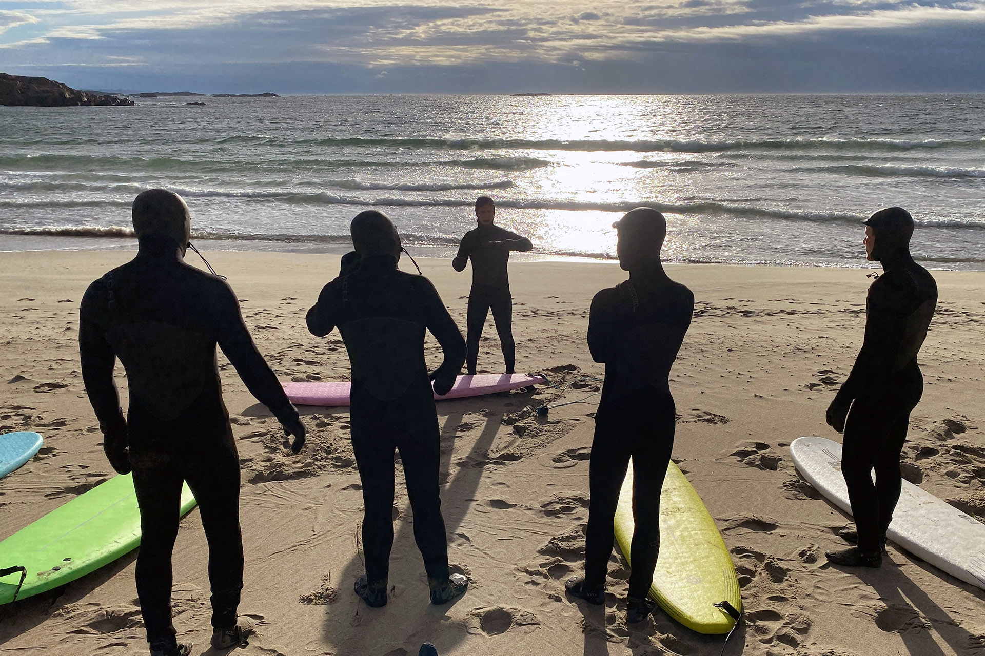 Bilde fra folk i våtdrakter på en strand som skal til å surfe