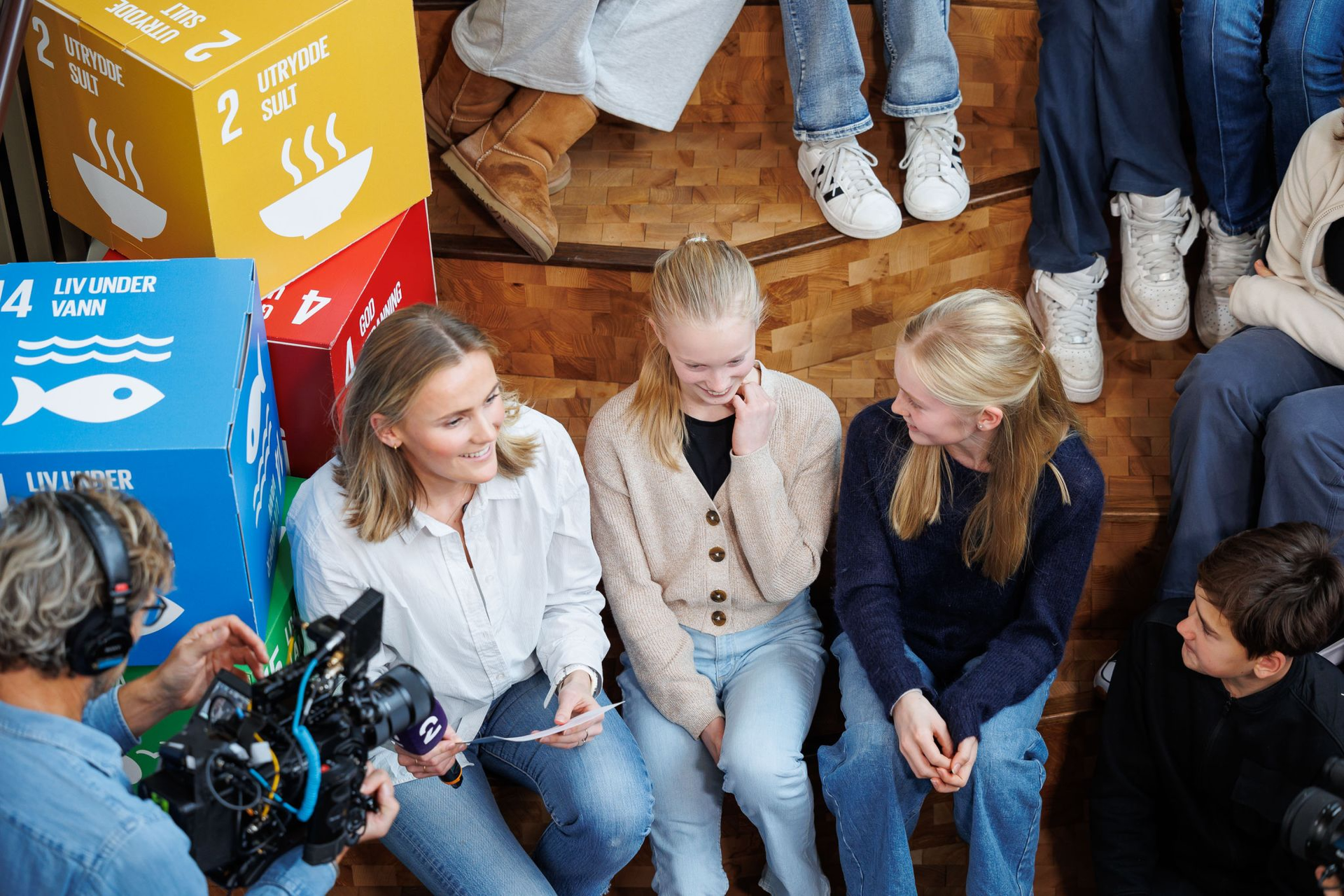 Bildet inneholder programleder Camilla som intervjuer to ungdommer på FN-dagen i 2023
