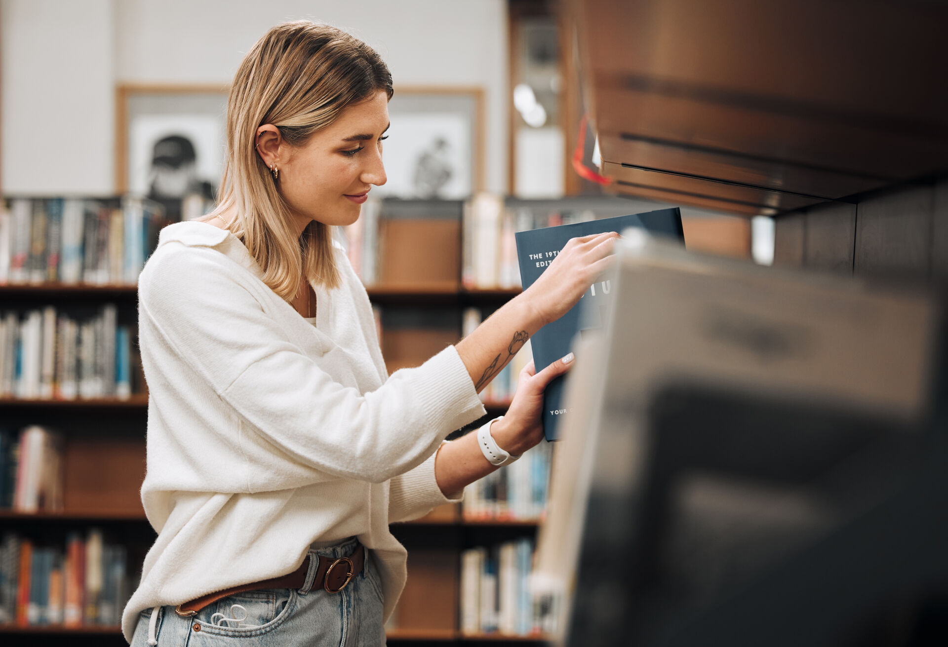 Historiestudent leter etter bok i en hylle på biblioteket