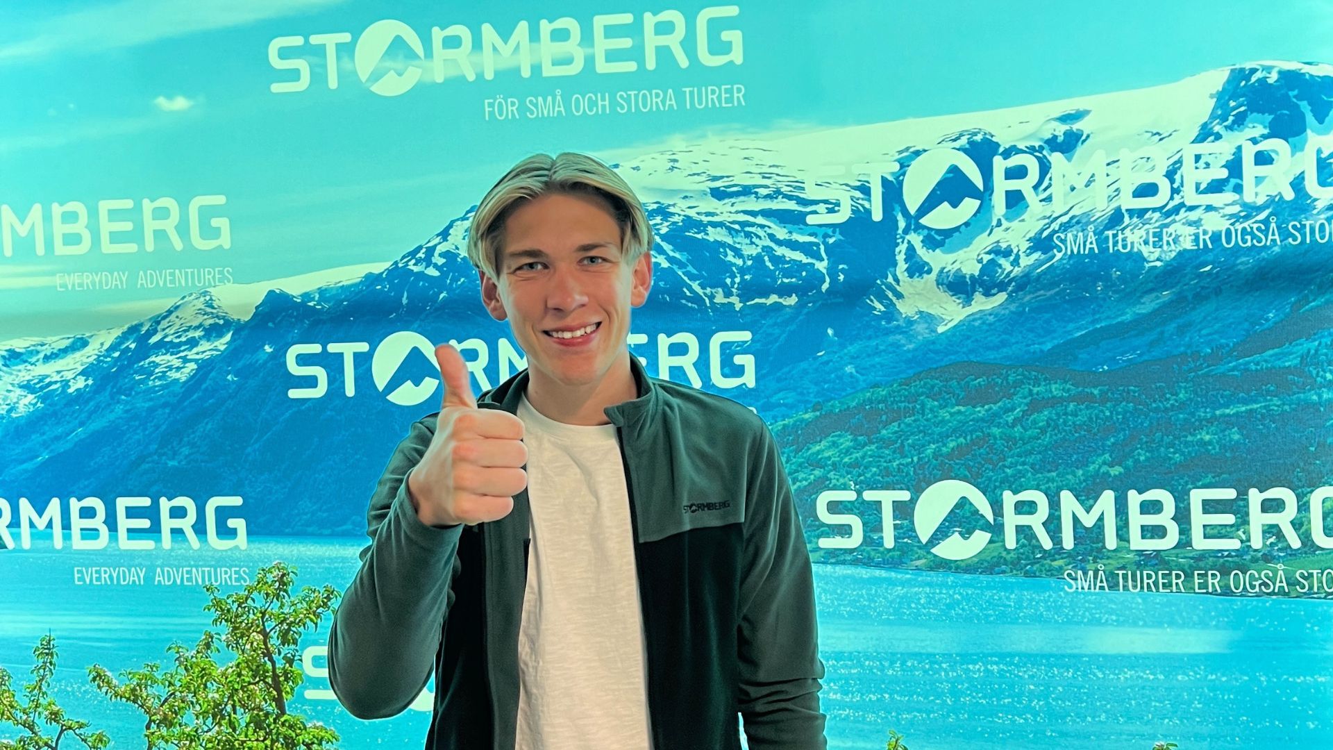 Portrettfoto av Kristoffer Ask foran en vegg med Stormberg-logo