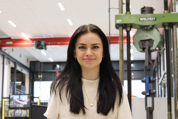 UiA-student Ida Zarei Johansen står foran noen maskiner med armene i kors