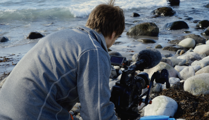 Mann med videokamera ved havet