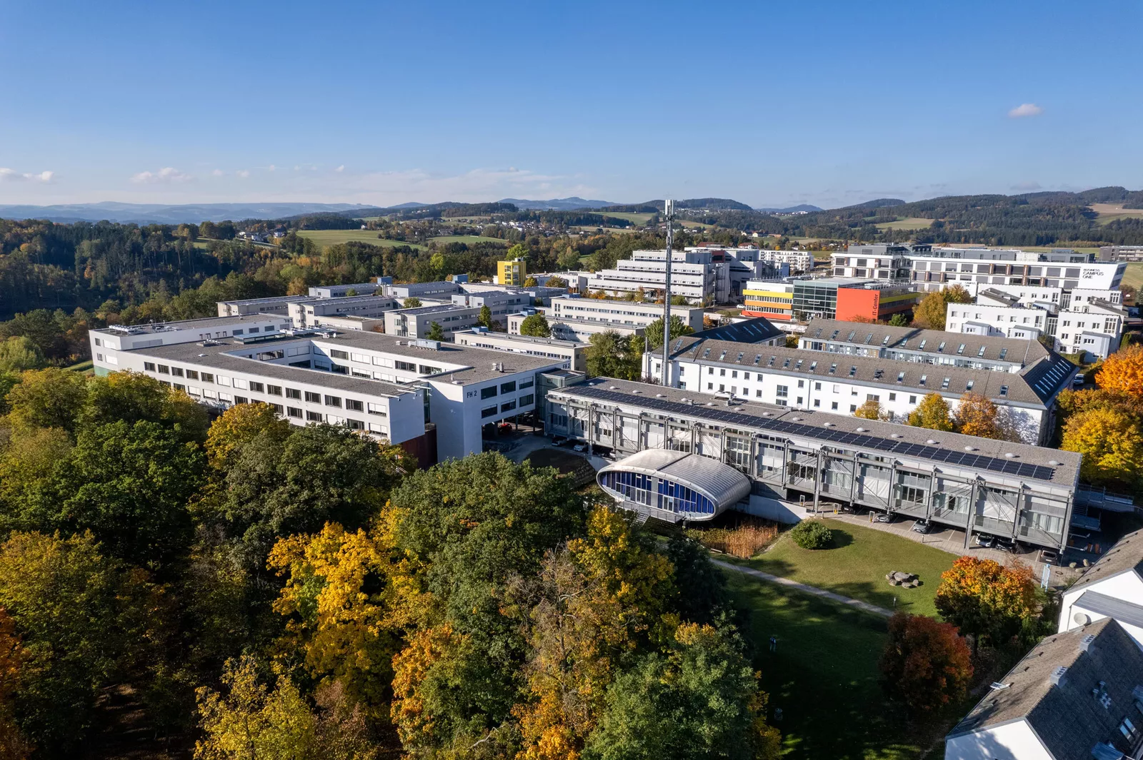 Fugleperspektiv av campus Hagenberg omgitt av mange trær og jorder.