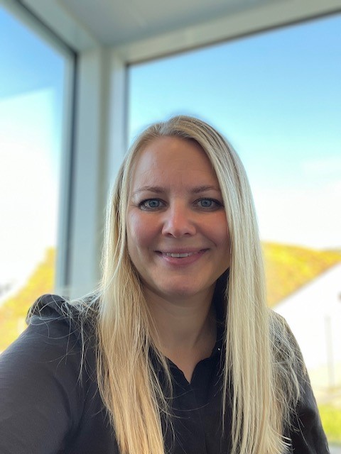 Blond kvinne med mørk topp smiler